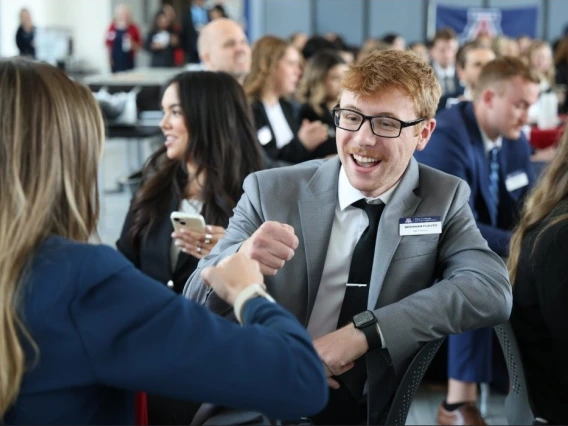 Students wearing business formal attire chatting at an in-person event.