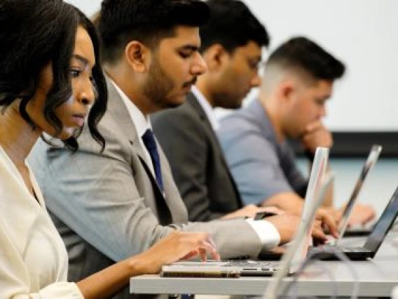 Students working on their laptops in a classroom setting.