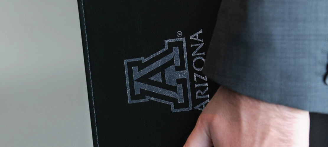 Student shown holding a University of Arizona notebook binder.