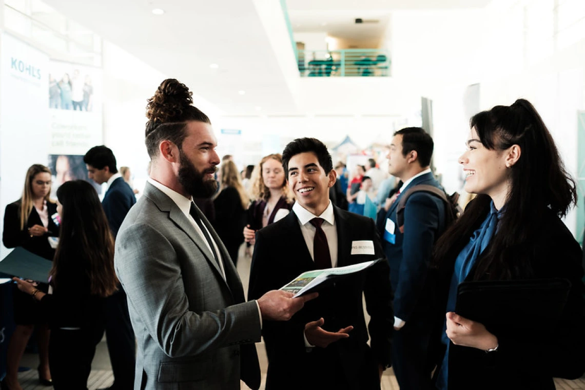 Students wearing business formal attire networking at an event.