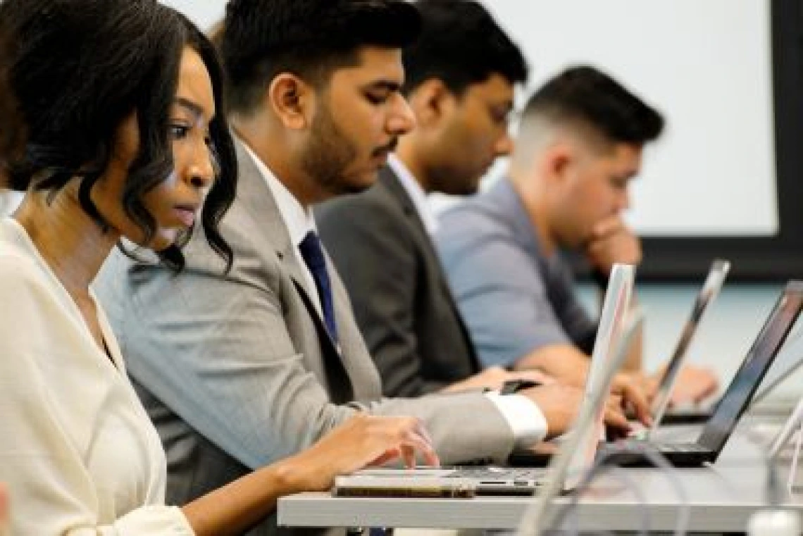 Students working on their laptops in a classroom setting.