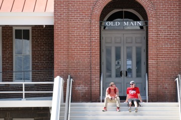 Students relaxing on the steps of Old Main while wearing red UArizona t-shirts