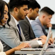 Students working on their laptops in a classroom setting.