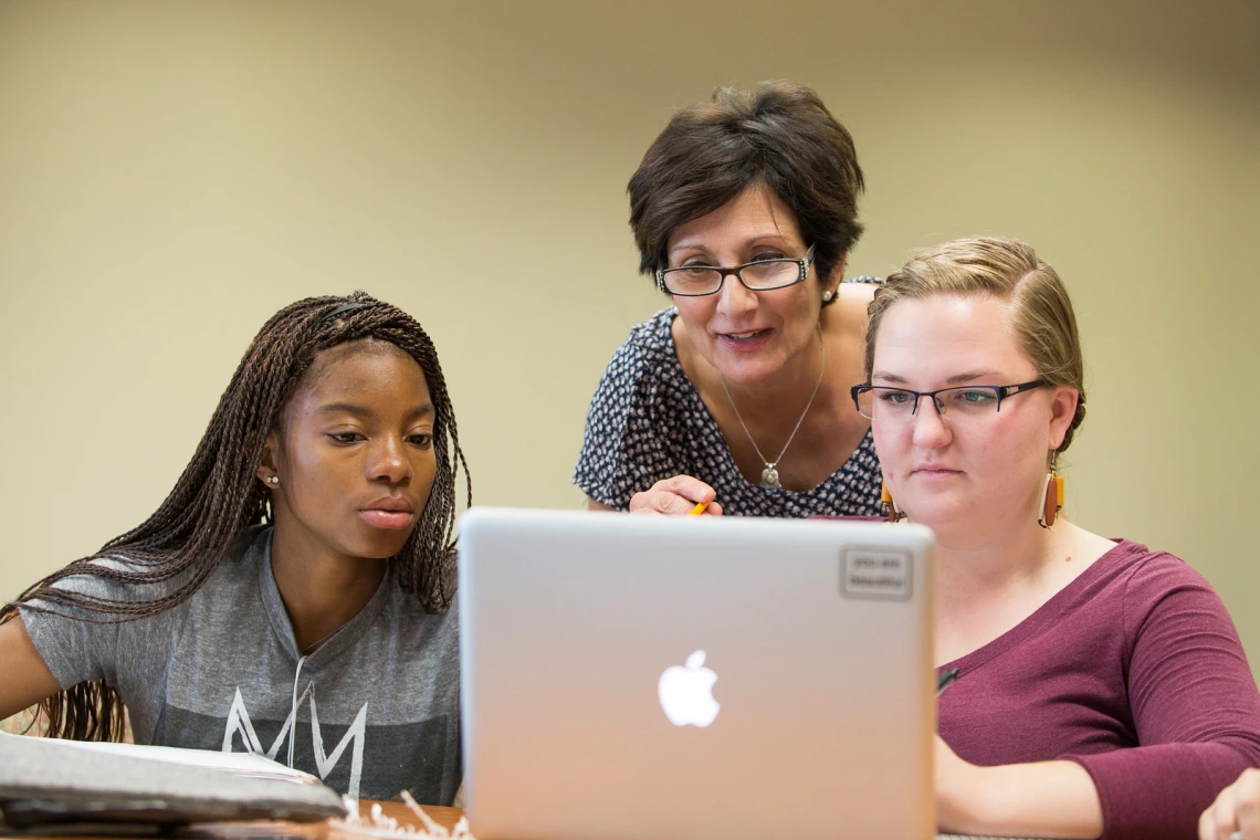 Three people looking at a computer