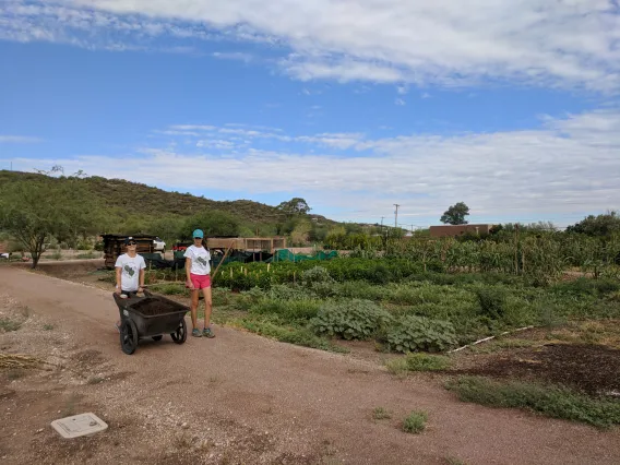 Coverdell Fellows pushing wheelbarrow at Mission Garden